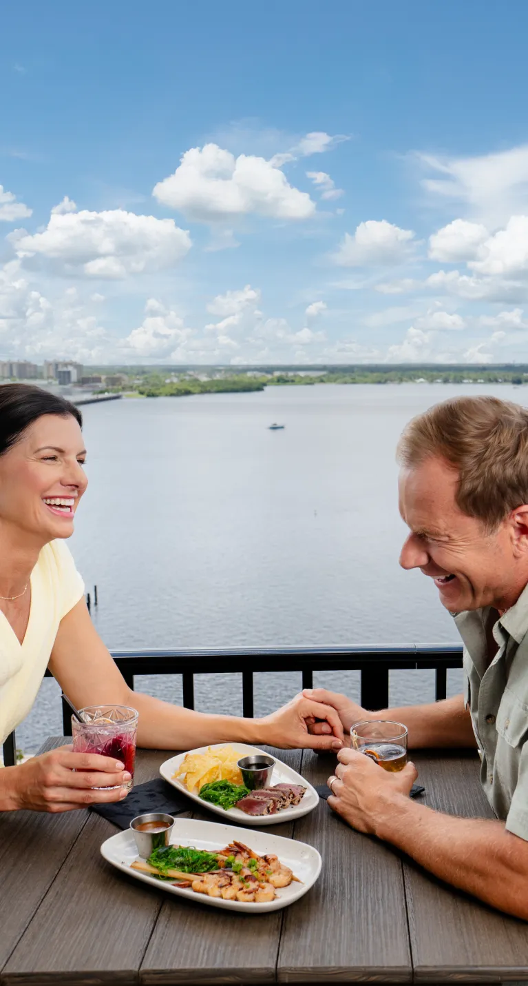 A couple enjoys dinner at a rooftop bar overlooking the river in downtown Fort Myers