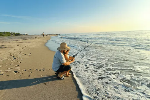 A family fishing on a beach next to the ocean