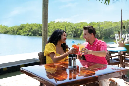 A couple toasts at a waterside restaurant
