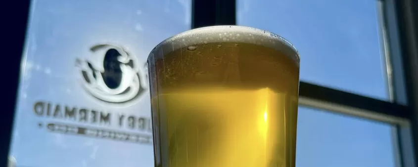 A glass of beer sitting next to a window