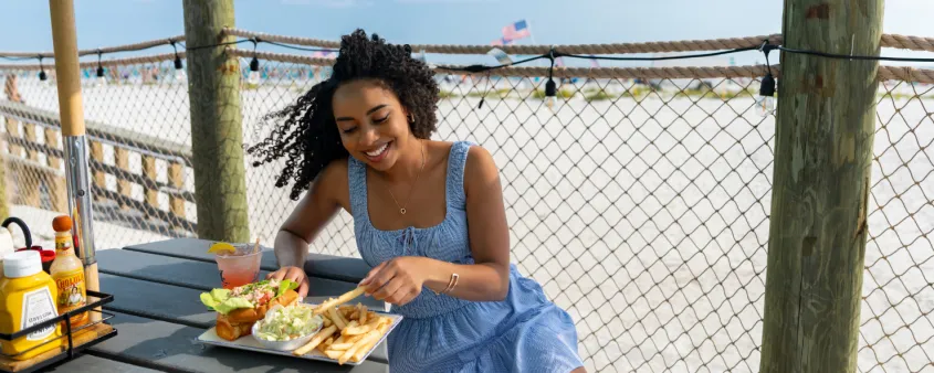 A woman enjoys dining on the beach