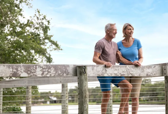 Couple stands on a boardwalk overlooking the water.